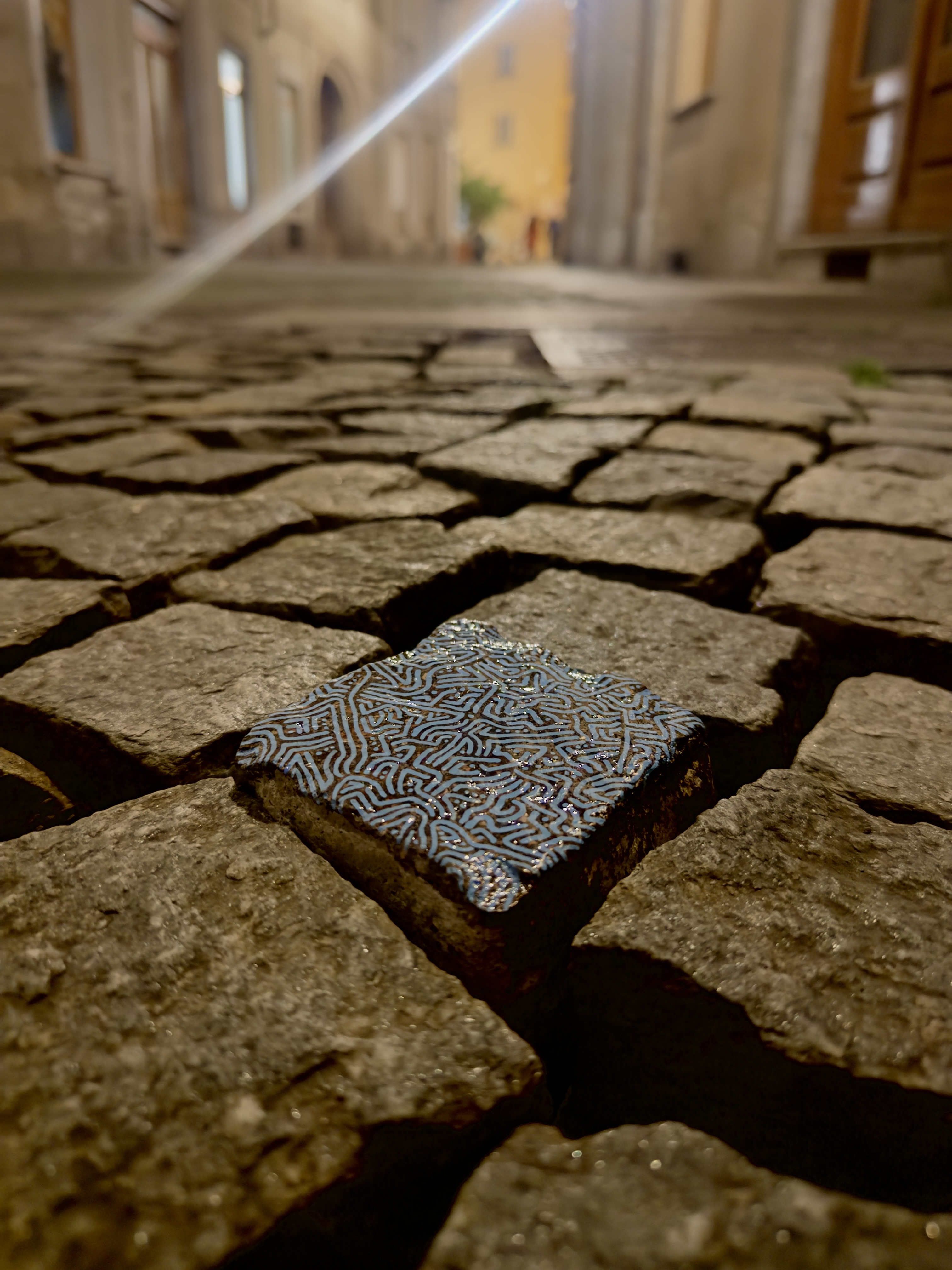 Sanpietrino dipinto a mano tra pietre stradali in una via notturna